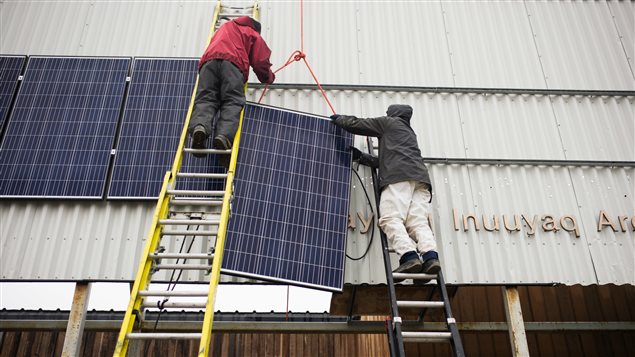  Vancouver Renewable Energy Coop Solar Installer, Duncan Martin (L) and Logistics Coordinator for Greenpeace Canada, Claude Beausjour install solar panels at the Clyde River community centre.