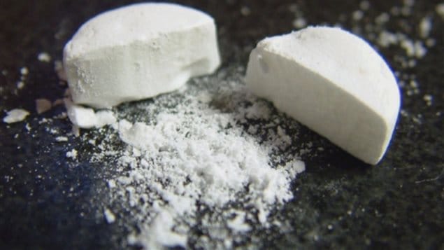 There are warnings that the fentanyl crisis has made its way east from western Canada. We see a white pill that has been split in half. White powder sits in front of the two parts of the pill.