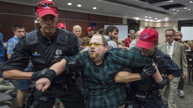 A protester is removed after disrupting public hearings on the $15.7-billion Energy East pipeline project.