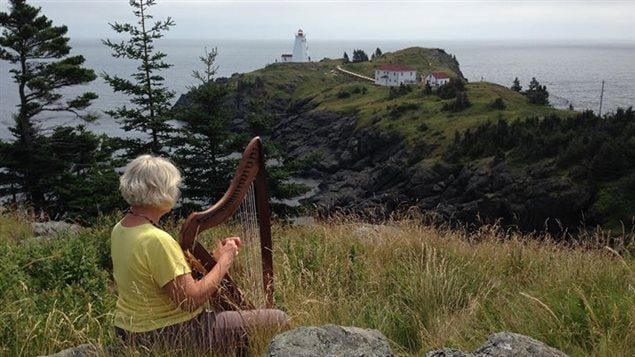 Sharon Johnston with a Celtic harp, overlooking Swallowtail Lightstation, Grand Manan Island, New Brunnwick