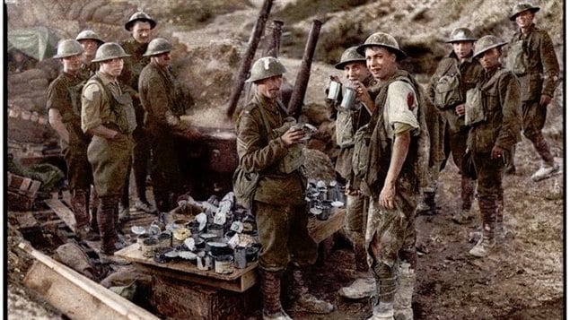 Colourized image of original black and white photo showing a soldier slightly wounded in shoulder and leg drinking tea about 100 yards behind the front line at Hill 70, Aug.1917