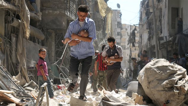 Deux hommes transportent des bébés dans les rues d’Alep après un bombardement contre un quartier rebelle. 