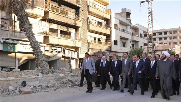 A photo from the Syrian official news agency SANA shows Syrian President Bash al-Assad walking through a suburb of Damascus on September 12, 2016. Shortly after the ceasefire took effect he said His government is determined to ‘reclaim every area from the terrorists, and to rebuild’ the country.