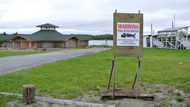 La communauté de Grassy Narows et une enseigne qui indique de ne pas consommer de poisson de la rivière.