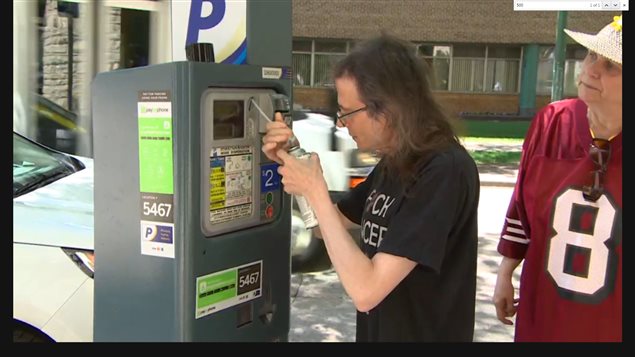 Protesting parking fees at hospitals, Collin Kennedy uses a tin of insulating foam, which will harder to a solid mass, to fill and block the coin slots in a parking machine at the cancer treatment centre in Winnipeg