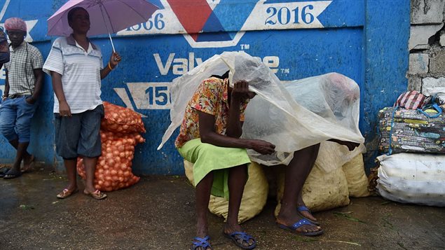  Women protect themselves from the rain with plastic in the Haitian capital of Port-au-Prince, on October 3, 2016. 