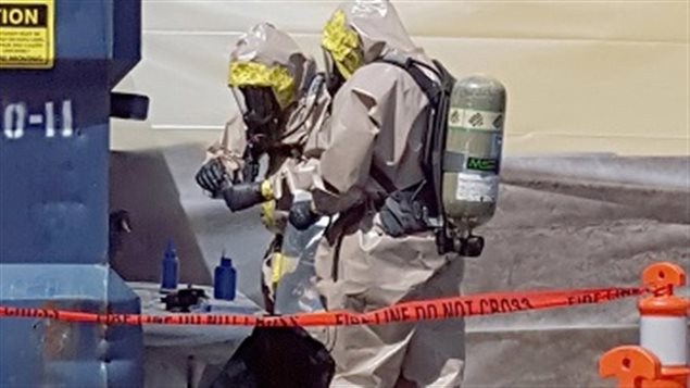 June 27, 2016, RCMP in hazmat suits in Vancouver inspect containers (bliue bottles on table) containing deadly carfentanil. The plastic bottles were shipped from China labelled as printers ink to avoid inspection by border control agents.