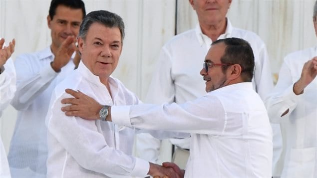 哥伦比亚总统桑托斯（左）与游击队领袖握手言欢