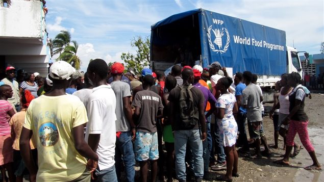 Haitianos hacen fila junto a los camiones del Programa Mundial de Alimentos para recibir comida tras la serie de desastres naturales que devastaron la isla.