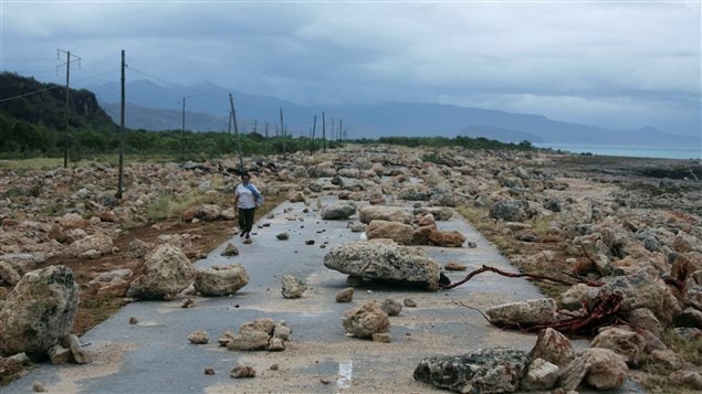 A woman walks on a highway blocked by rocks on the coast of Guantanamo province. 