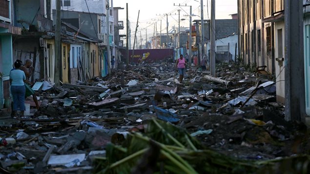 A woman walks along a street covered in debris in Baracoa.
