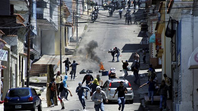Jóvenes enmascarados se enfrentan a las fuerzas del orden en San Cristobal, Venezuela.