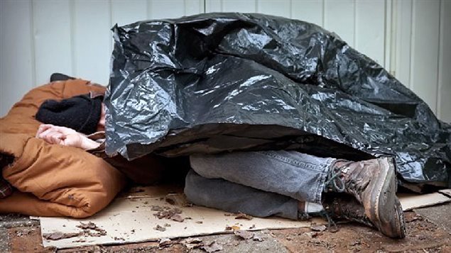 un homme dort dans la rue sous un sachet poubelle