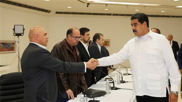 El presidente venezolano Nicolás Maduro (der) le da un apretón de mano a Jesús "Chúo" Torrealba, secretario ejecutivo de la Mesa de Unidad Demoncrática, MUD.