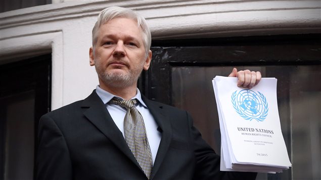 El fundador de WikiLeaks, Julian Assange, en el balcón de la embajada de Ecuador en Londres, muestra un documento de un Grupo de trabajo de Naciones Unidas sobre las detenciones arbitrarias, que dice que su detención debería terminar. 