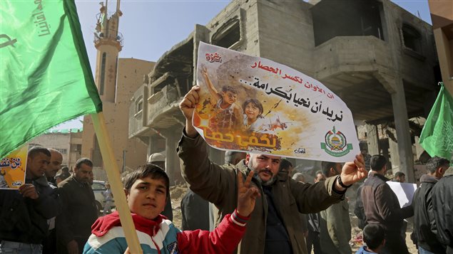 Palestinian Hamas supporters protest against the decision by the U.N. Relief and Works Agency to suspended an aid program for Gaza residents displaced by the 2014 war, in Beit Hanoun, northern Gaza Strip, Friday, Jan. 30, 2015. The UNWRA said it suspended the program because of a large shortfall in funds from donor countries. Arabic on poster reads *It’s time to break the siege, we want to live with dignity, enough siege.*