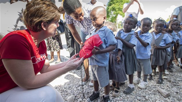 International Development Minister Marie-Claude Bibeau hands out pouches of school supplies to children where the school was reopened following the passing of hurricane Matthew, in Camp Perrin, Haiti, on Thursday, November 17, 2016. 