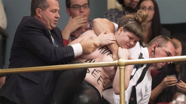 A topless Femen activist is carried out of the legislature visitor section by security after protesting the presence of the crucifix inside the legislature in Quebec City on Tuesday, October 1, 2013. 