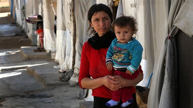 A displaced Iraqi woman from the Yazidi community, who fled violence between Islamic State (IS) group jihadists and Peshmerga fighters in the northern town of Sinjar, stands at a camp for internally displaced persons (IDP) in the Sharia area, some 15 kilometres from the city of Dohuk, on November 17, 2016.