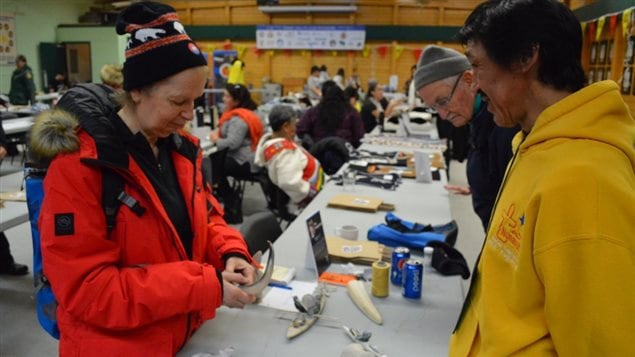  Ship tourists buying crafts in a remote viallge community centre. There are concerns that massive tourist influx can change the culture and lifestyle while adding to climate change through plane and ship exhaust and with waste releases into Arctic water.