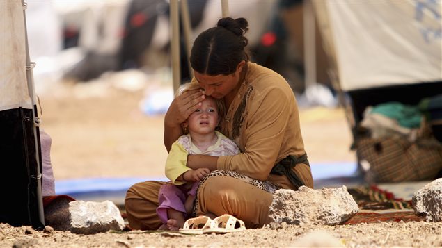 A refugee woman from the minority Yazidi sect, who fled the violence in the Iraqi town of Sinjar, sits with a child inside a tent at Nowruz refugee camp in Qamishli, northeastern Syria August 17, 2014.