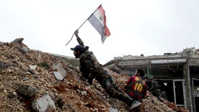 جنديّ سوري يرفع علم بلاده في أحد أحياء حلب الشرقيّة