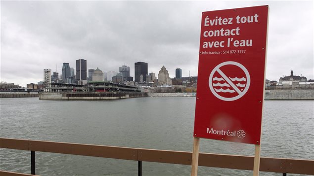 A sign warns to avoid contact with the water along the shore of the St. Lawrence River Friday, November 13, 2015 in Montreal. The city dumped billions of litres of raw sewage into the river while repairs were being made to the sewage collectors.