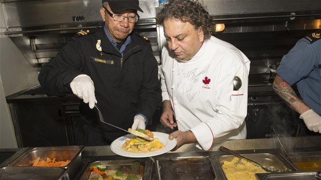Celebrity chef, Vikram Vij (right) and Lieutenant (Navy) Haupi Tombing, padre onboard Her Majesty’s Canadian Ship (HMCS) CHARLOTTETOWN serve supper for the ship’s crew during Operation REASSURANCE, December 17, 2016.