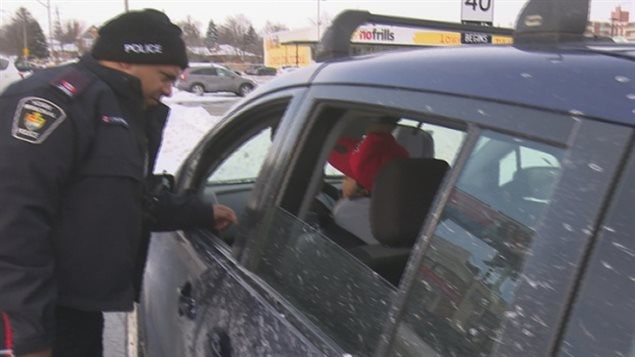 A police officer stops a driver for using a mobile phone and gives him a ticket for distracted driving.