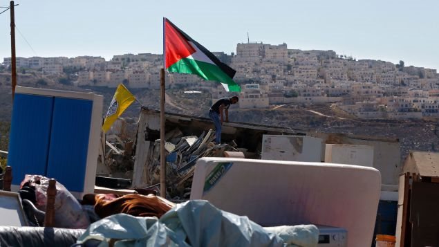 Palestino busca en los escombros de su casa demolida en Jerusalén Este, mayoritariamente árabe, en el barrio Beit Hanina, situado cerca de la colonia Ramat Shlomo, que se ve en el fondo.
