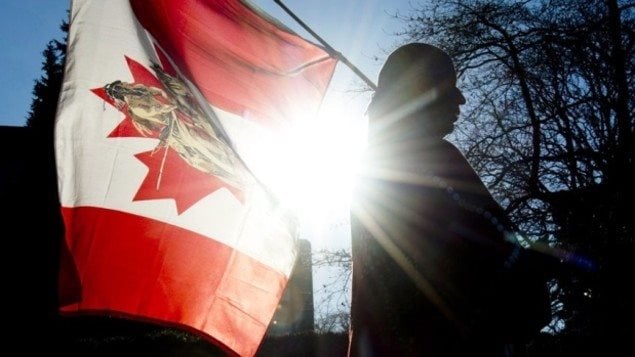 مواطن من أبناء السكّان الأصليّين يحمل علم كندا