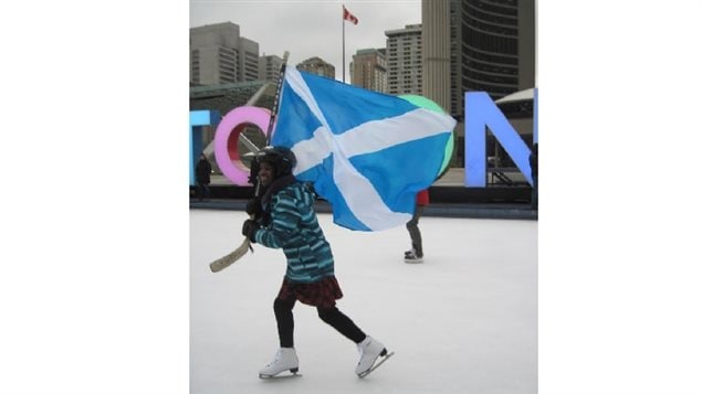 2016, Nathan Phillips Square Toronto. A schoolgirl (in a kilt) skates with the Scottish flag in a kilt skate promotional event. Toronto has officially signed on for a Sir John Kilt Skate this year.