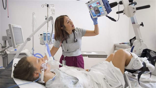 Prof. Michelle Kho monitors a patient on a ventilator as she cycles while lying in bed.