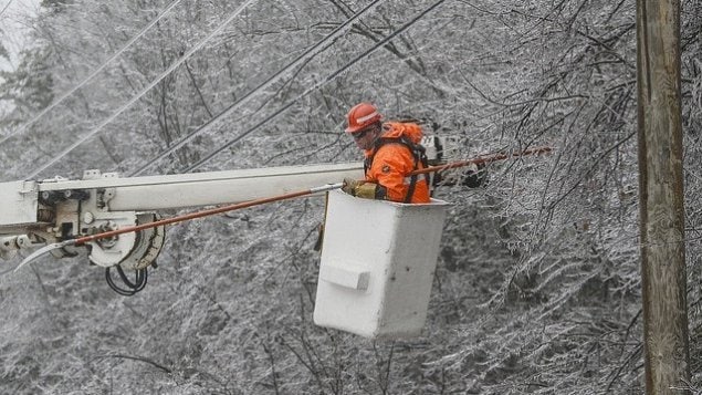 أحد فنّيي شركة الكهرباء العامة في نيو برونزويك (Énergie NB Power) يقوم بإصلاح الأضرار اللاحقة بالشبكة جراء عواصف الأمطار الجليدية