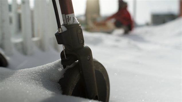 A close up of a walker wheel buried in snow.
