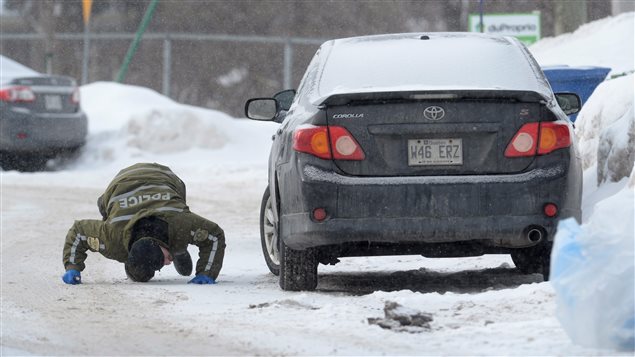A police officer looks for evidence Monday under a car in the area of a Quebec City mosque where six people died after two masked men entered the building and began shooting Sunday night. Five worshippers are in critical condition. Authorities fear the number of dead could rise.