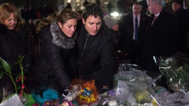 Justin Trudeau et son épouse Sophie Grégoire Trudeau placent des fleurs sur les lieux d’un monument commémoratif populaire lors d’une veillée à Québec lundi soir.  (Paul Chiasson / Presse canadienne)