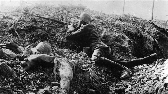 Vers 1916, un soldat allemand tient son arme dans une tranchée à Fort de Vaux, en France, à côté du corps d'un soldat français. Vers 1916, un soldat allemand tient son arme dans une tranchée à Fort de Vaux, en France, à côté du corps d'un soldat français.