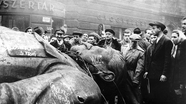 Des révolutionnaires hongrois entourent une statue renversée de Staline devant Théâtre national de Budapest, le 24 octobre 1956. Des révolutionnaires hongrois entourent une statue renversée de Staline devant Théâtre national de Budapest, le 24 octobre 1956.