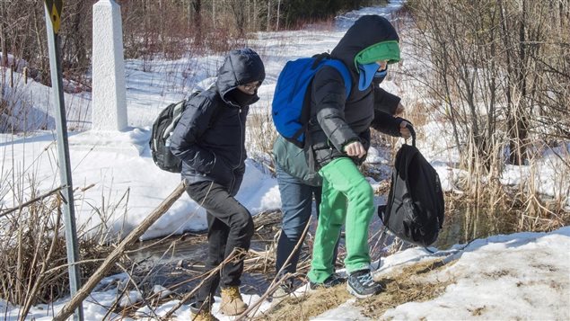 Migrantes cruzando a pie ilegalmente la frontera entre EE.UU y Canadá para pedir asilo.