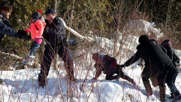 Des agents de la Gendarmerie royale du Canada (GRC) aident un enfant d’une famille qui prétendait être du Soudan alors qu’ils traversent la frontière entre les États-Unis et Hemmingford, au Canada, de Champlain à New York. 