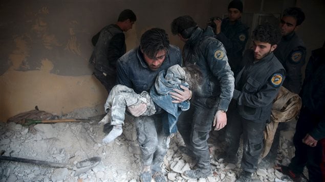 A man carries a child that survived from under debris in a site hit by what activists said were airstrikes carried out by the Russian air force in the town of Douma, eastern Ghouta in Damascus, Syria January 10, 2016.