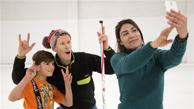 A Yazidi Kurdish woman and her son pose for a photo with curling club member Jim Creeggan (centre).