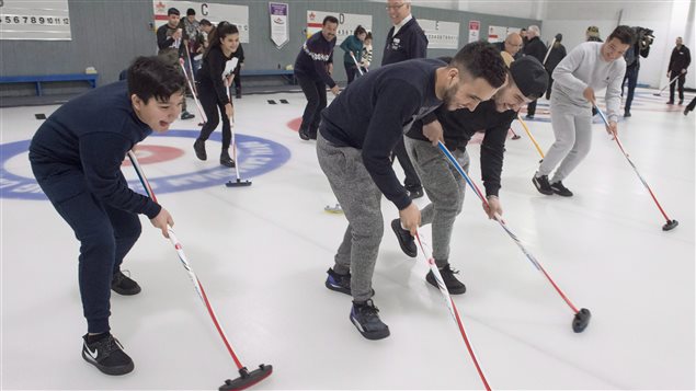 Refugees took to the ice with brooms to learn about balance when curling.