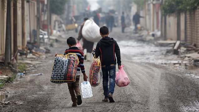 Civiles cargados con ayuda humanitaria en el distrito Al Ghizlane, mientras avanzan las tropas de las fuerzas iraquíes en Mosul Oeste, el 20 de marzo de 2017.