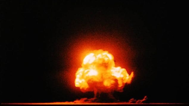 Photographie en couleur de la première explosion nucléaire lors de l’essai Trinity le 16 juillet 1945 à Alamogordo au Nouveau-Mexique.