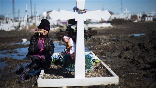 Six-year-old Chenille Tomagatick visits a relative’s grave at a cemetery in the northern Ontario First Nations reserve in Attawapiskat, Ont., on Tuesday, April 19, 2016. The James Bay community of 2,000 is under a state of emergency due to a spike in youth suicide attempts.