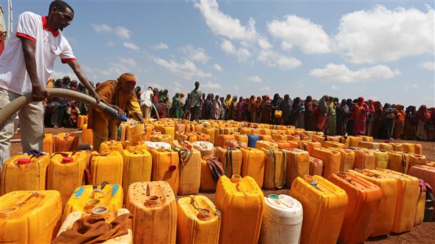 نساء صوماليات نزحن مع عائلاتهن جراء الجفاف ينتظرن الحصول على الماء في مركز توزيع تموله مؤسسة خيرية قطرية.
