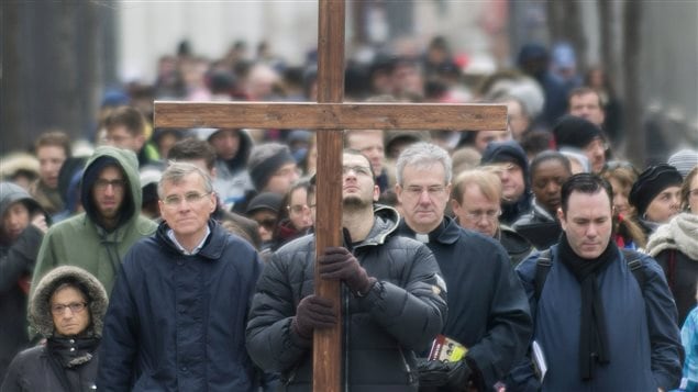 A man walks with a crucifix along with the faithful as they participate in the Way of the Cross on Good Friday in Montreal, April 18, 2014.