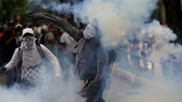 Manifestante regresa granada de gas lacrimógeno durante los enfrentamientos con las fuerzas del orden el 20 de abril 2017.